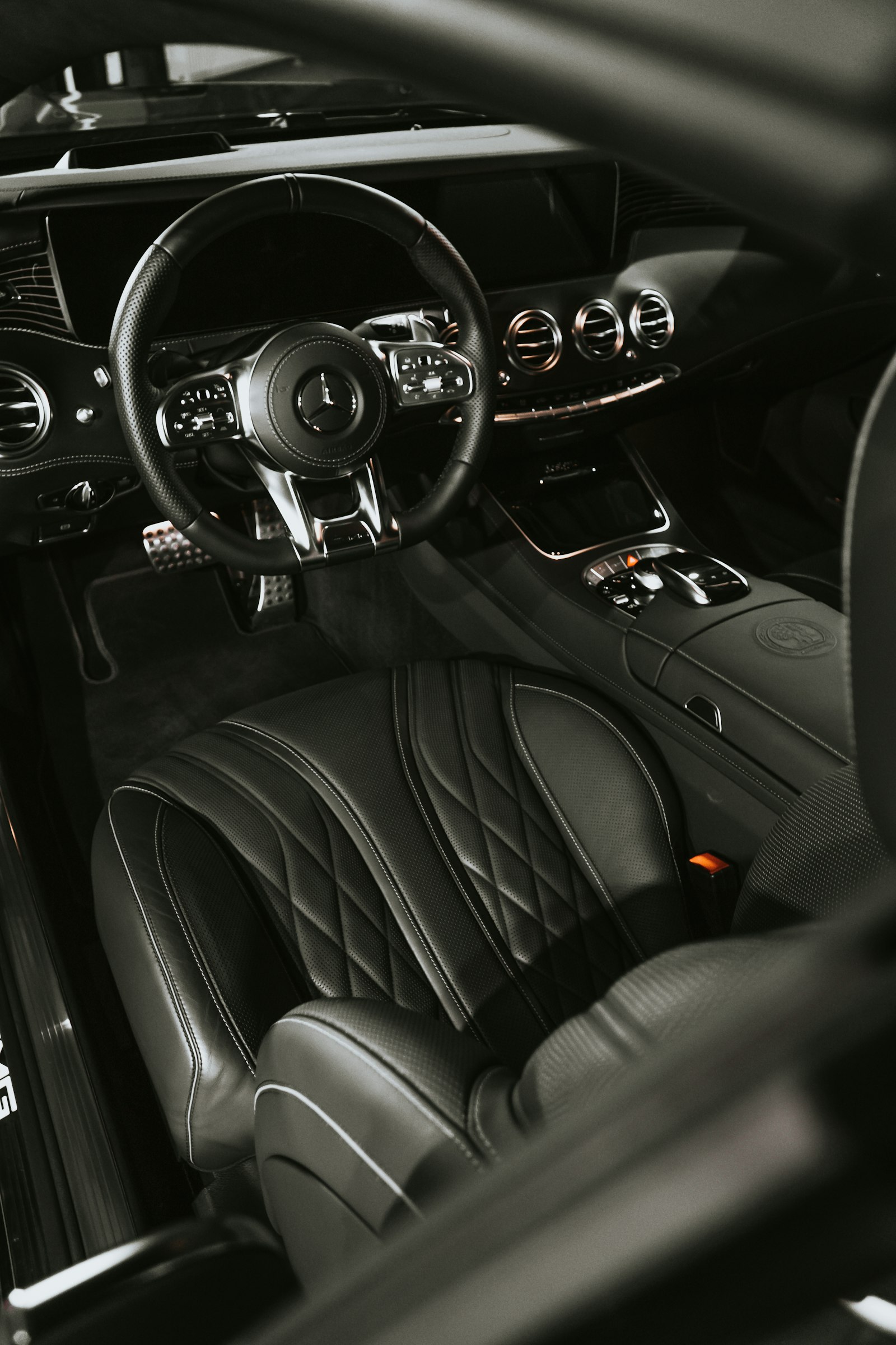 The dark leather cabin of a tinted car seen through the open driver’s door